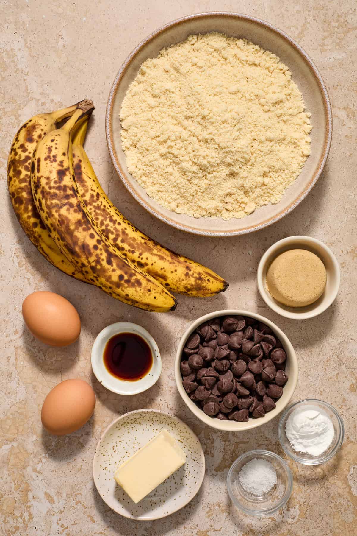 Butter, baking powder, bananas, brown sugar and other ingredients arranged on counter.