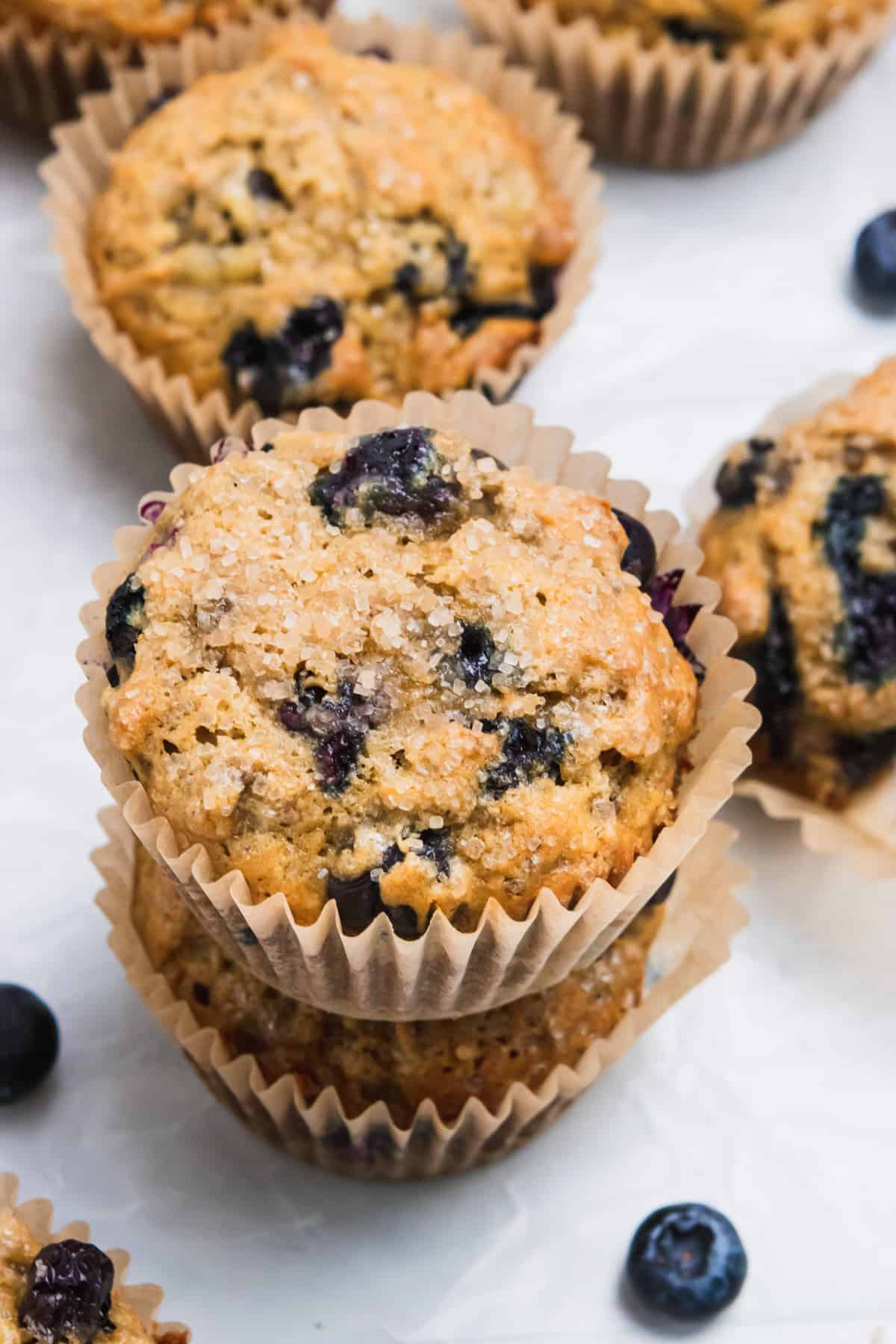 Stacked Blueberry banana muffins with blueberries on counter.