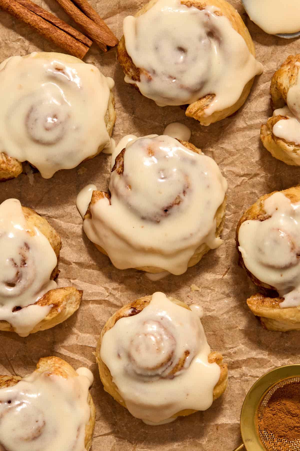 Iced cinnamon rolls on parchment paper.