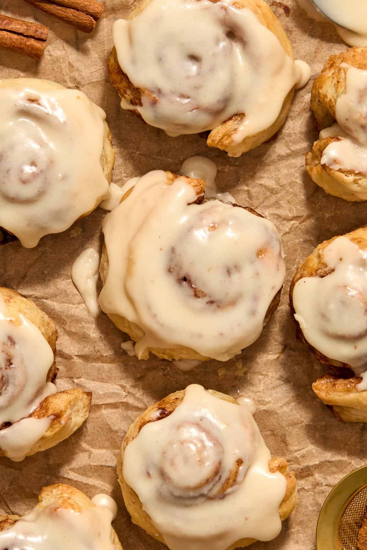 Cinnamon rolls with icing on top on parchment.