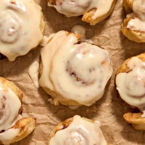 Maple icing topped puff pastry cinnamon rolls on parchment.
