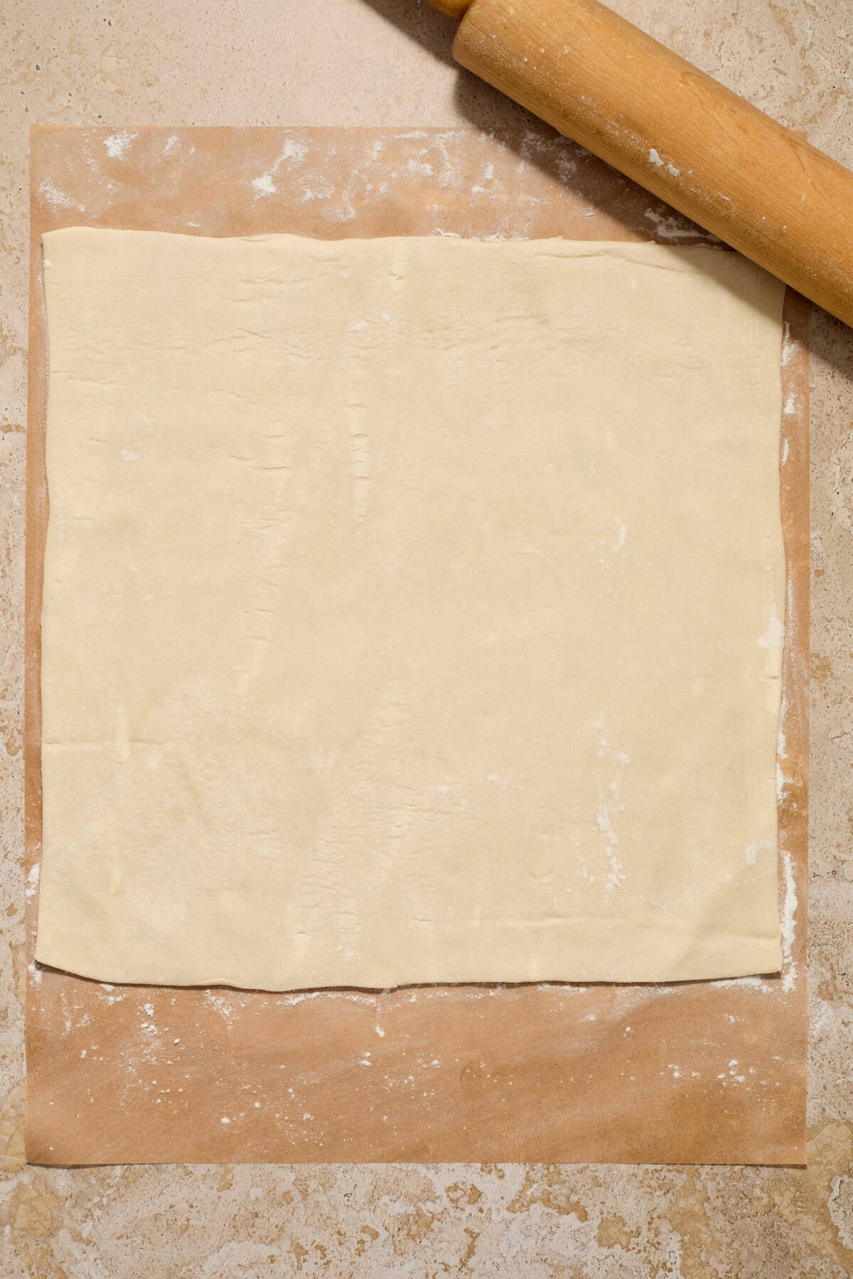Rolled puff pastry on lightly flour dusted parchment paper.