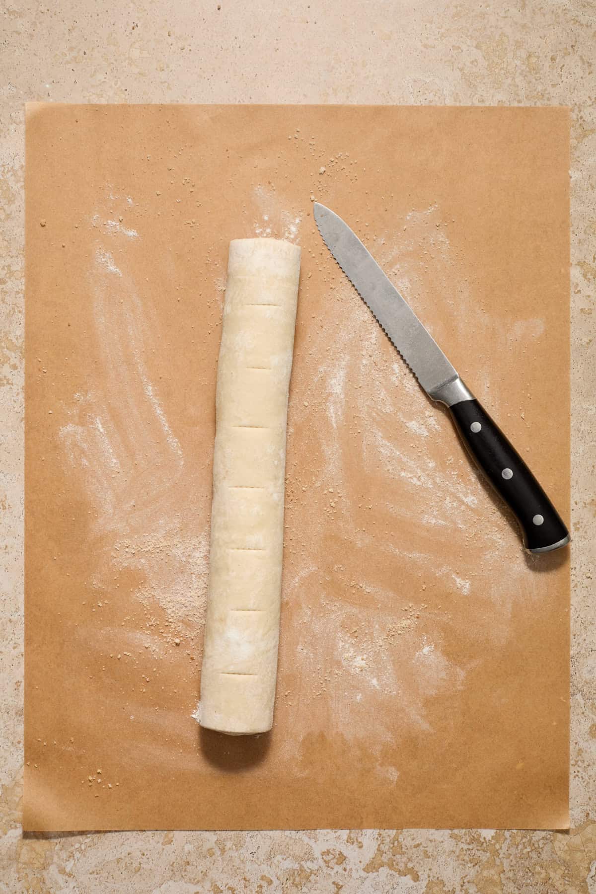 Lines cut on cinnamon roll log on parchment.