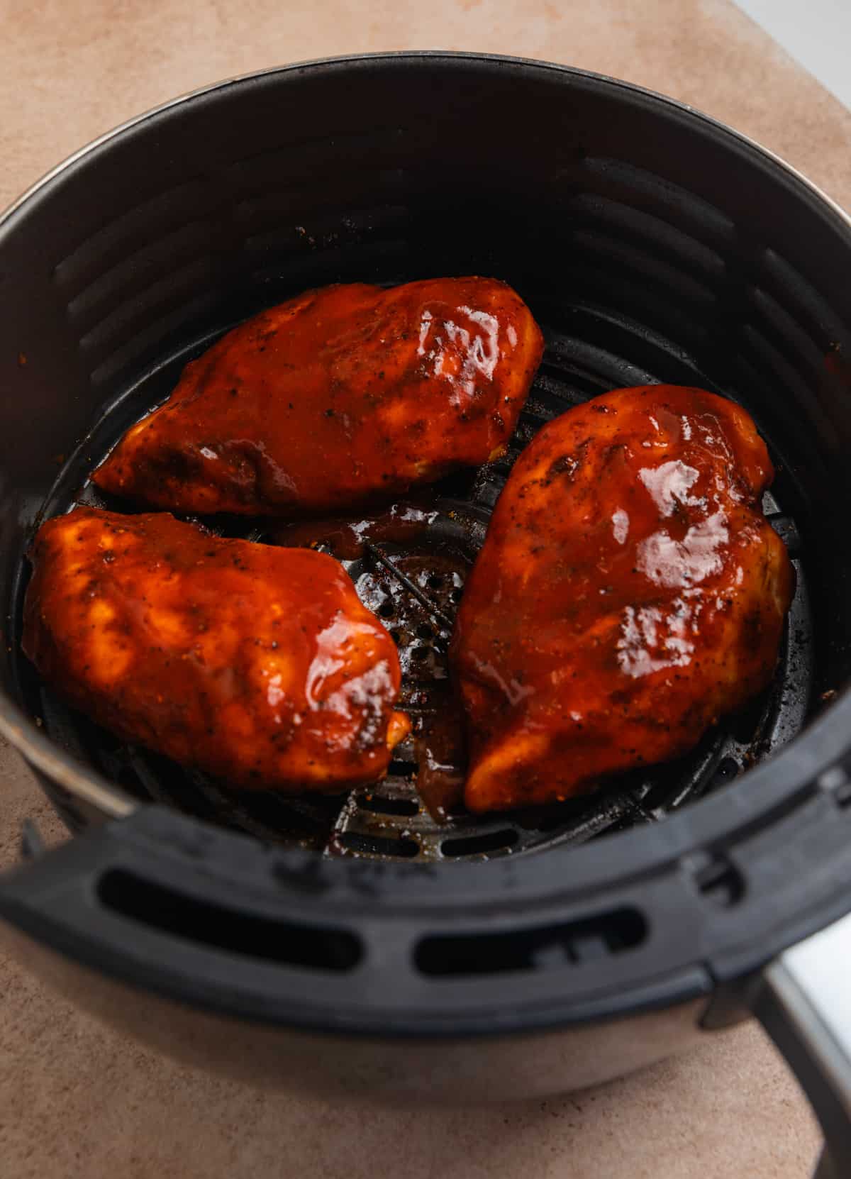 Chicken in air fryer cooked with barbecue sauce brushed on.