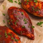 BBQ air fried chicken breasts arranged on parchment with chopped parsley.