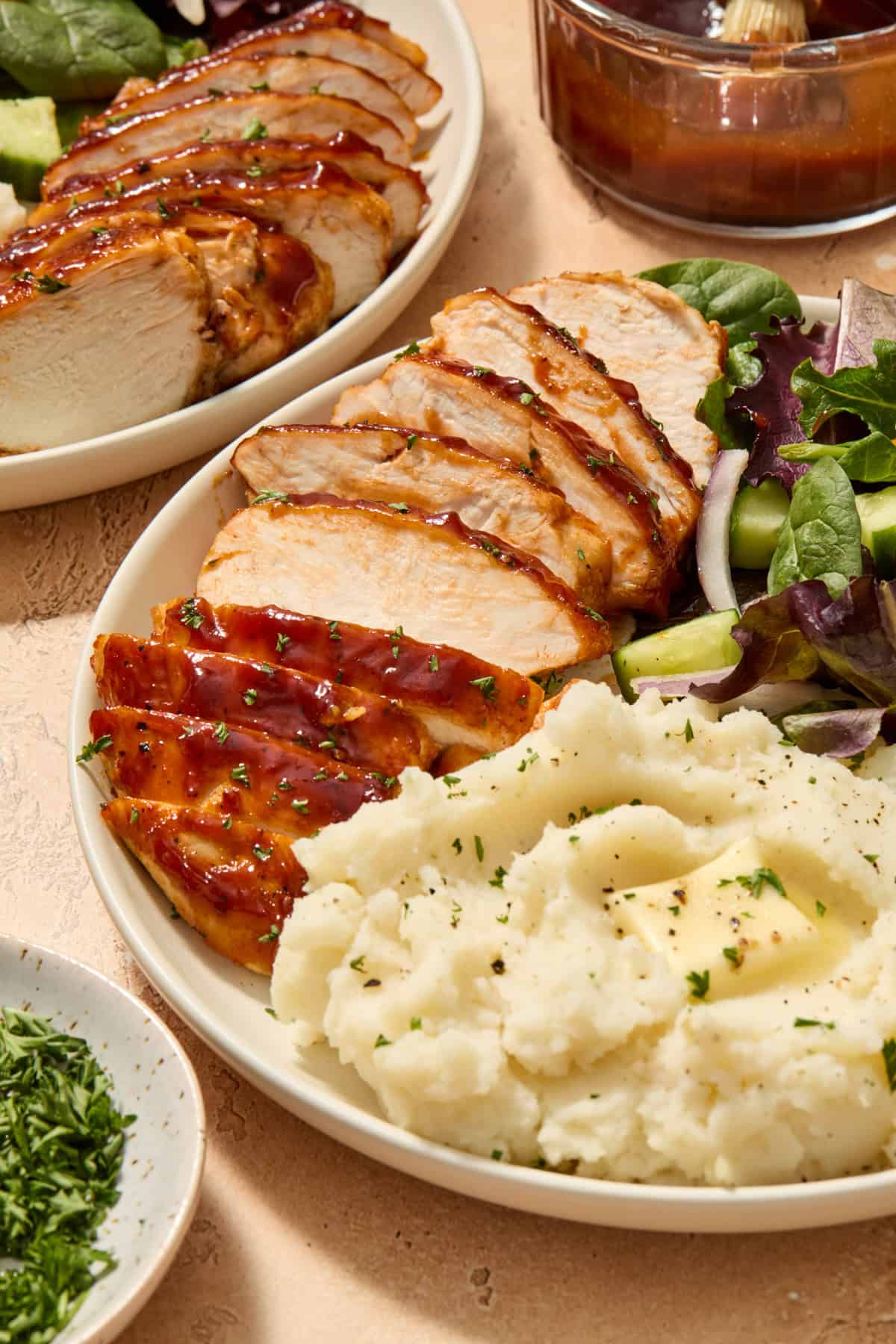 Sliced chicken on plate with mashed potatoes and salad.
