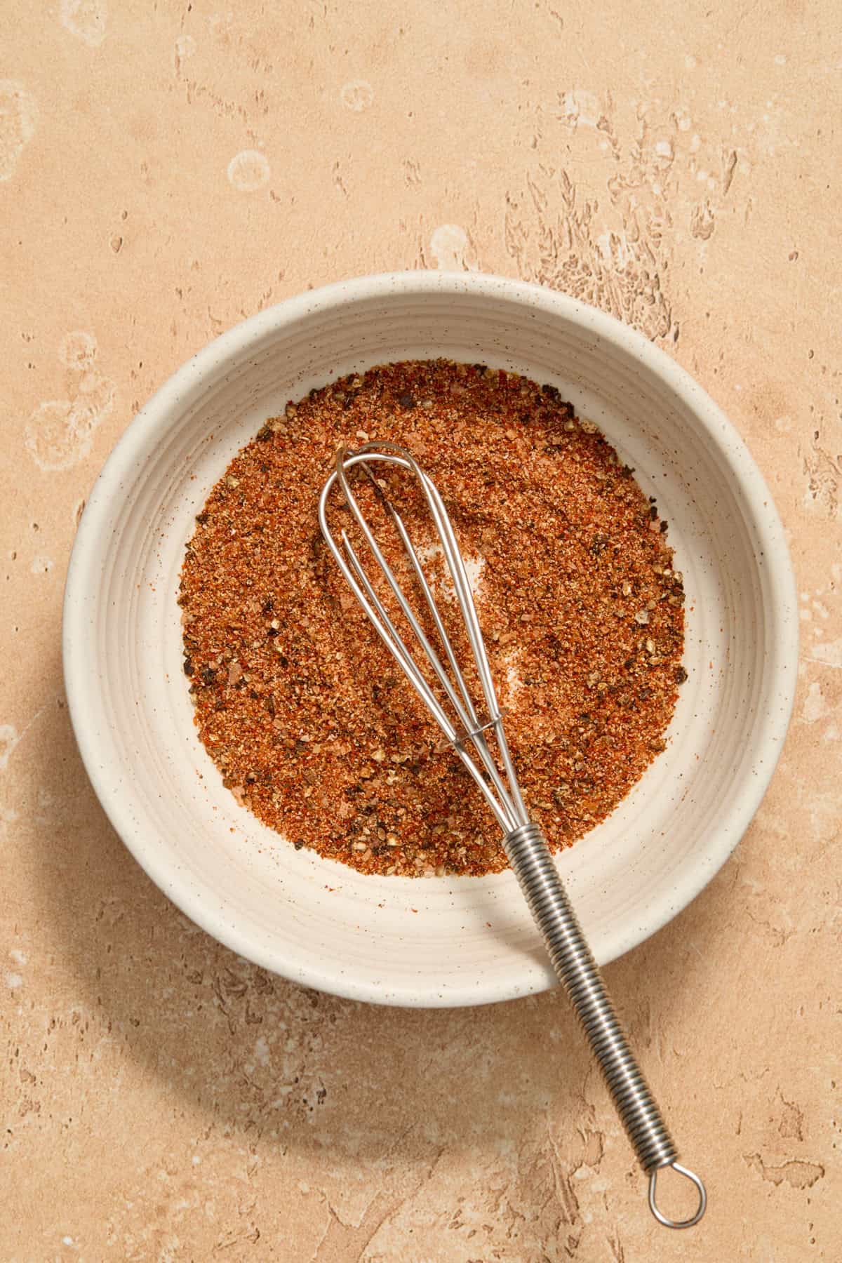 Bowl with whisk and chicken rub.