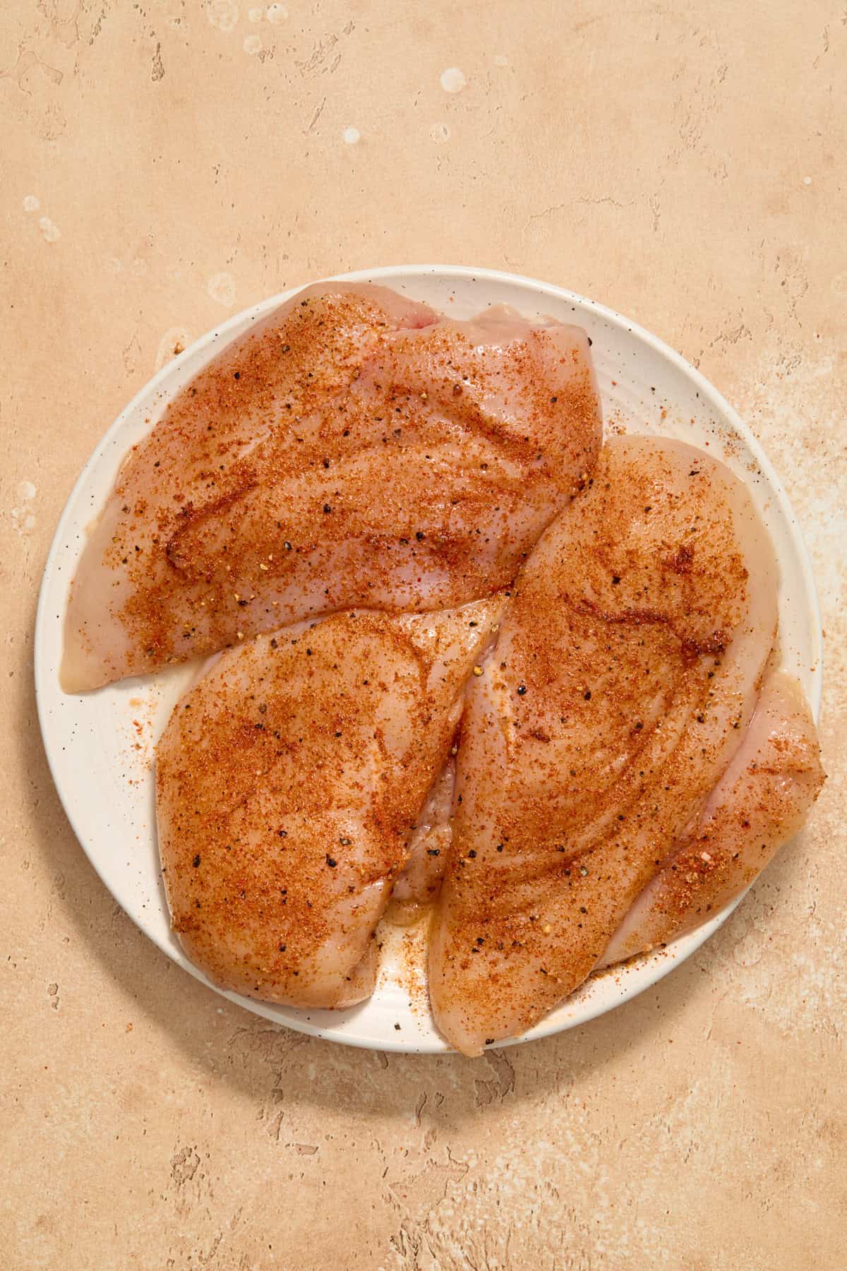 Seasoned chicken breasts on plate.