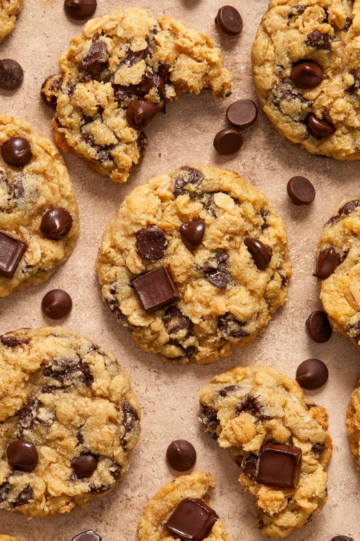 Oatmeal chocolate chip cookies arranged on surface with chocolate chips scattered.