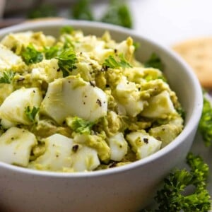Avocado egg salad in bowl with chopped parsley.