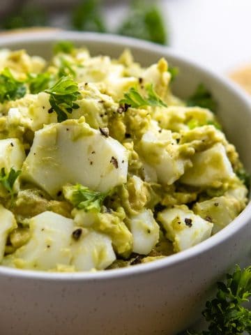Avocado egg salad in bowl with chopped parsley.