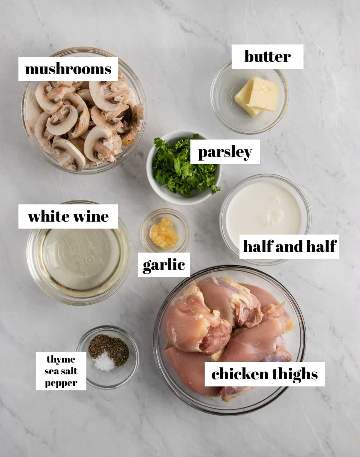 Chicken thighs, white wine, garlic, butter and ingredients labeled on counter.