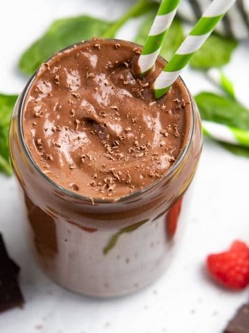 Chocolate raspberry smoothie with avocado and spinach on counter.