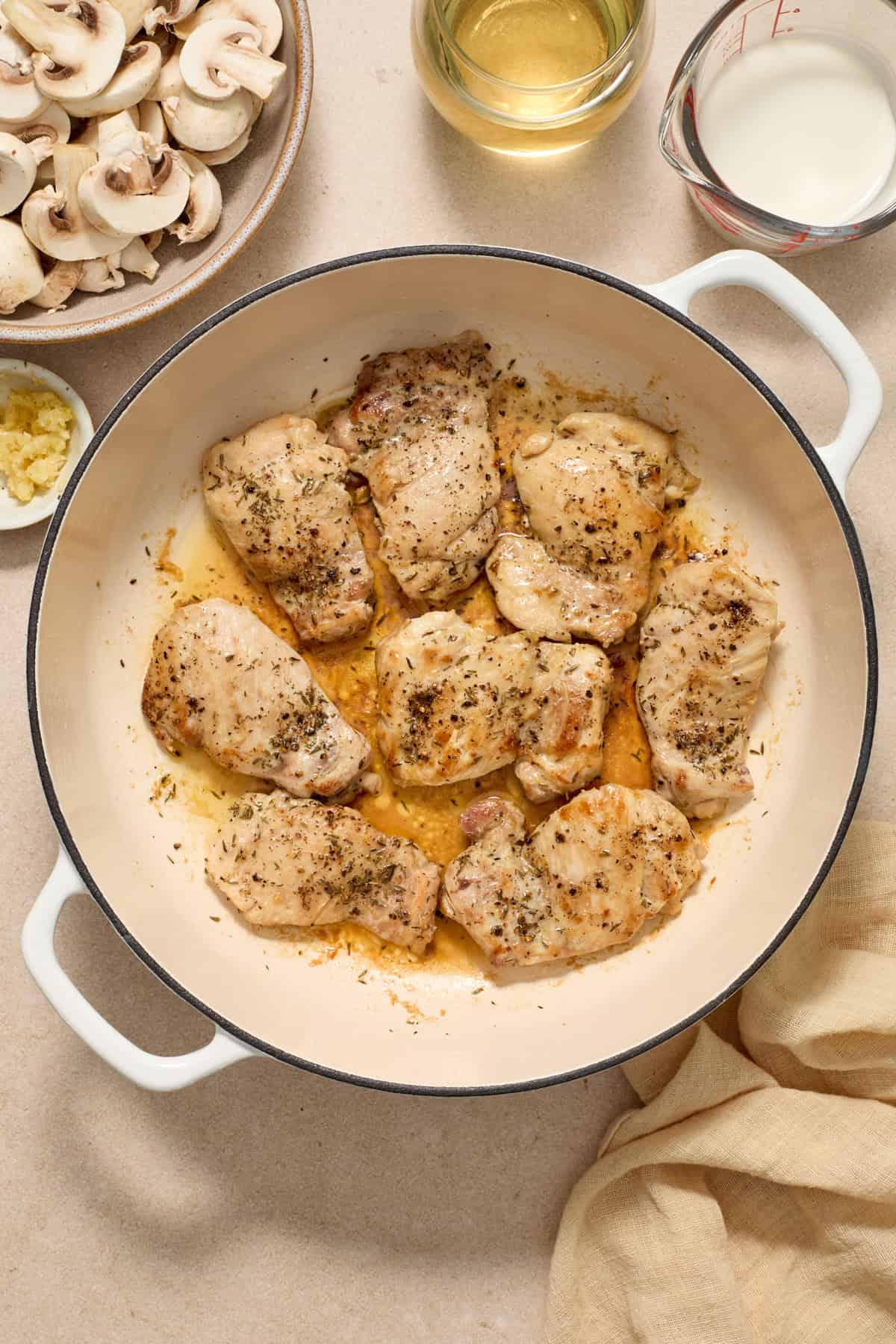 Seared boneless skinless chicken thighs in pan.