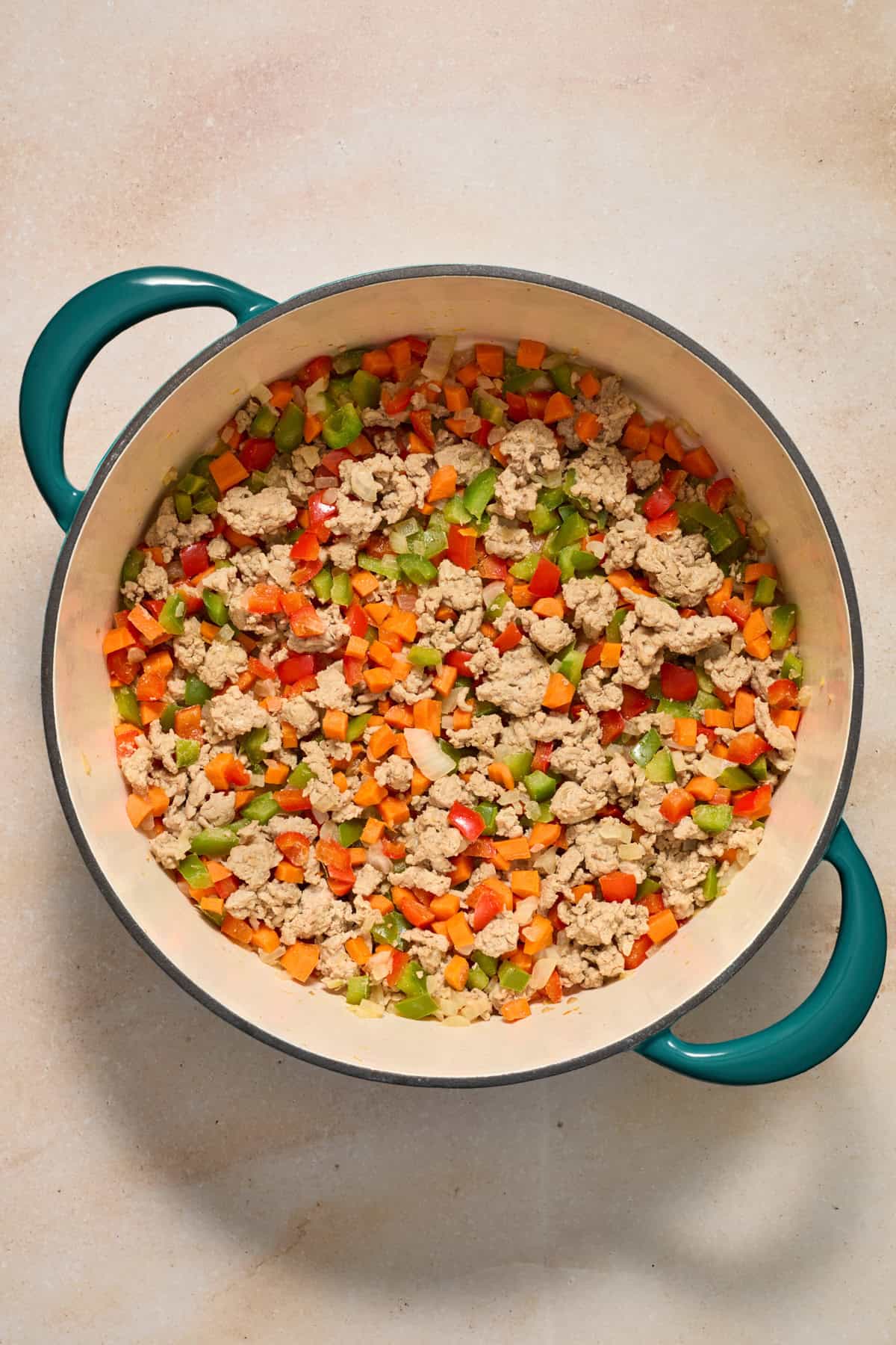 Browned ground turkey in pot with peppers and carrots.