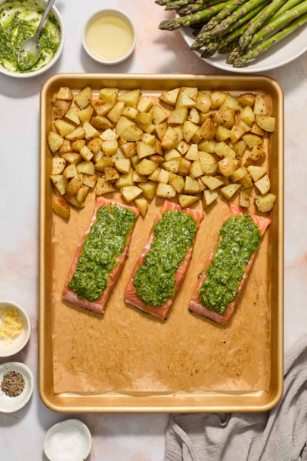 Sheet pan with salmon covered in pesto and roasted potatoes.