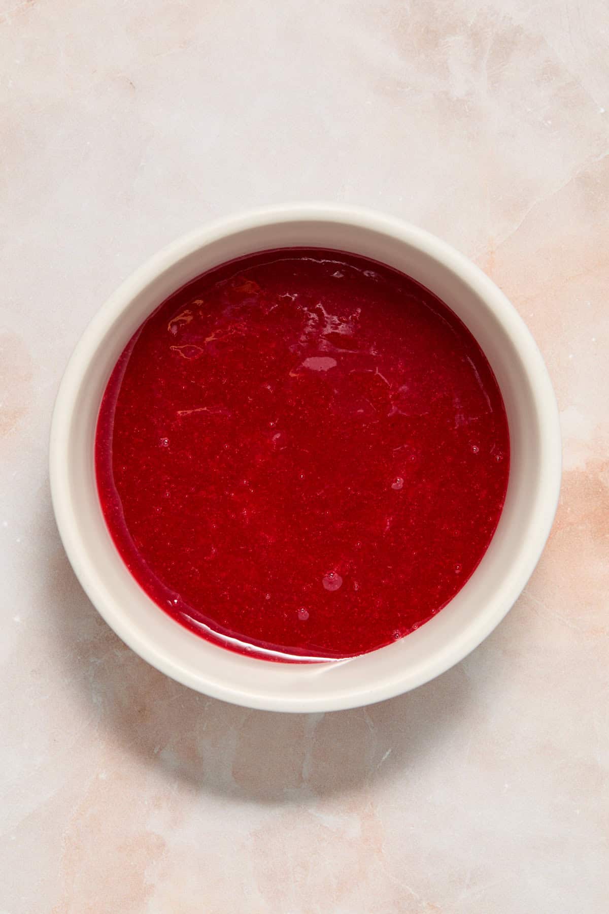 Homemade raspberry sauce in white bowl.
