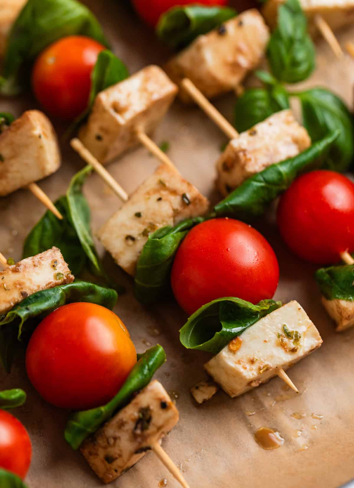 Tomato mozzarella basil skewers on parchment lined tray.