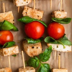 Caprese salad skewers lined on parchment.