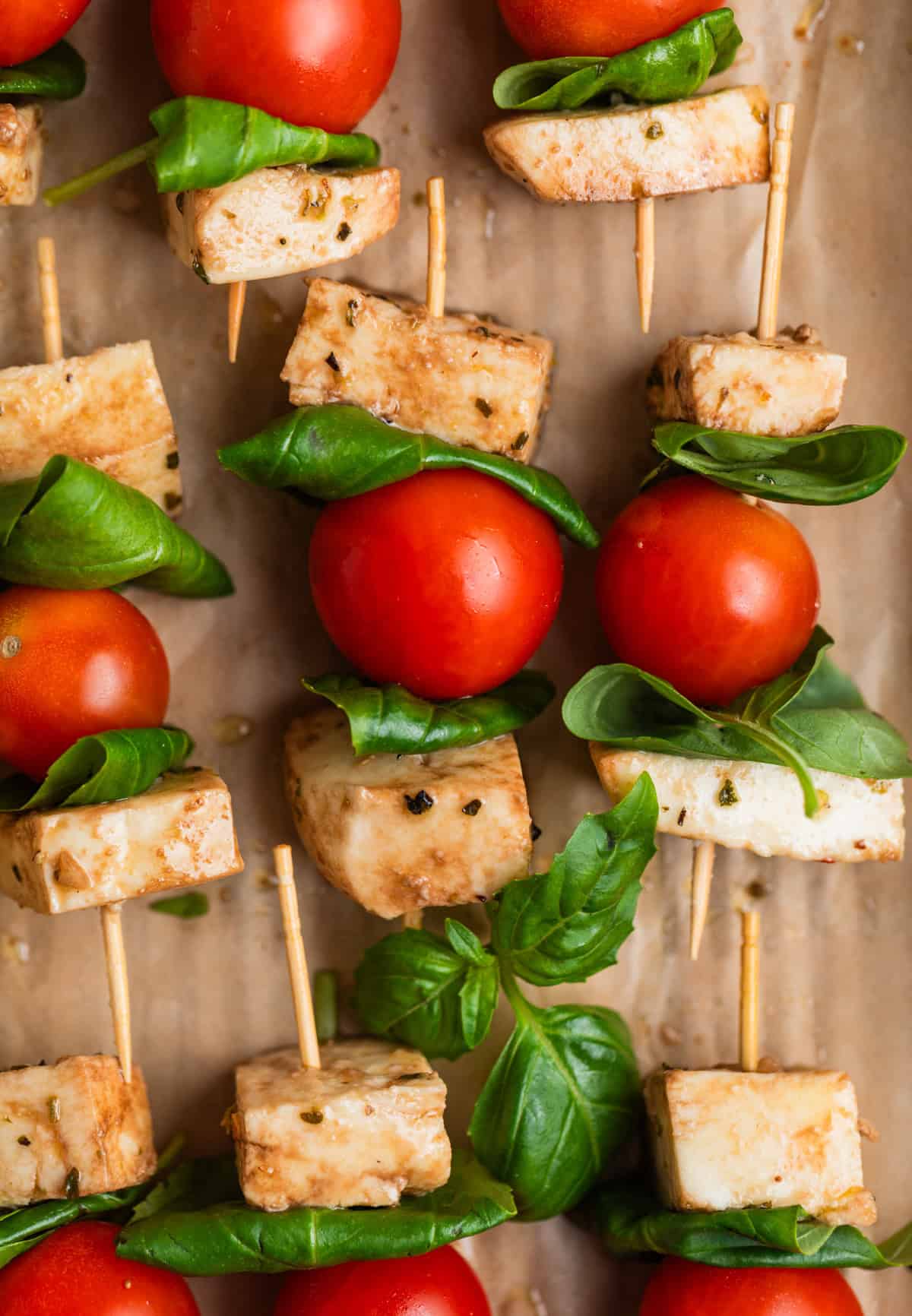Caprese salad skewers lined on parchment.