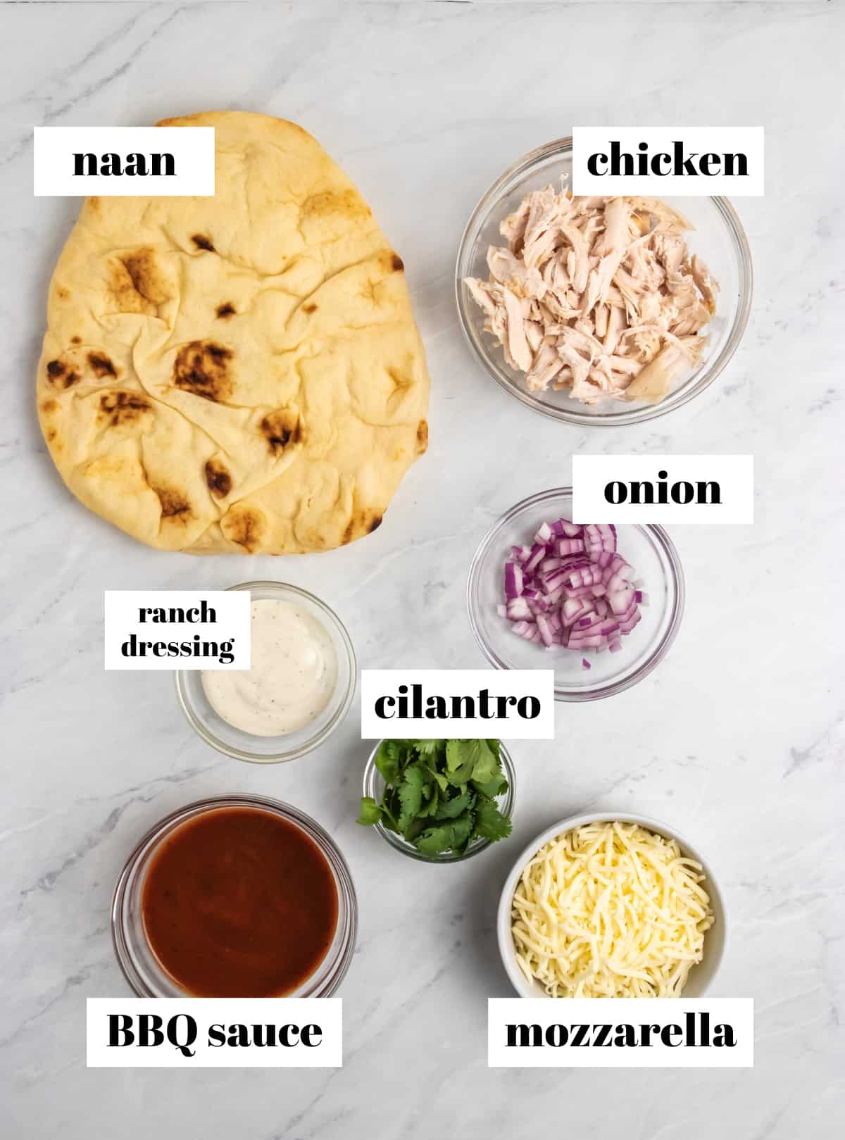 Naan, chicken, ranch, cilantro and other ingredients labeled on counter.