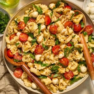 Tortellini caprese salad in bowl topped with balsamic glaze.