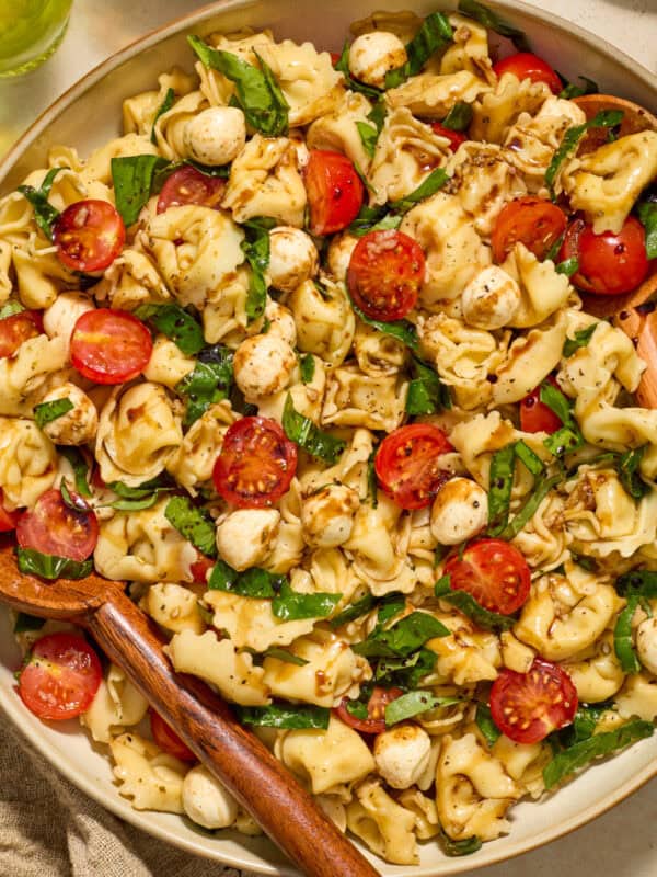 Tortellini caprese salad in bowl topped with balsamic glaze.