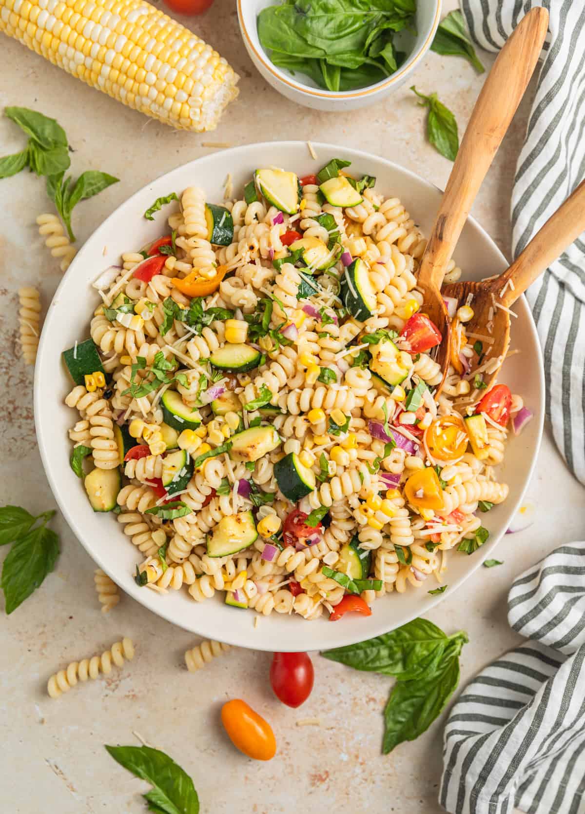 Overhead view of summer pasta salad with serving spoons in bowl.
