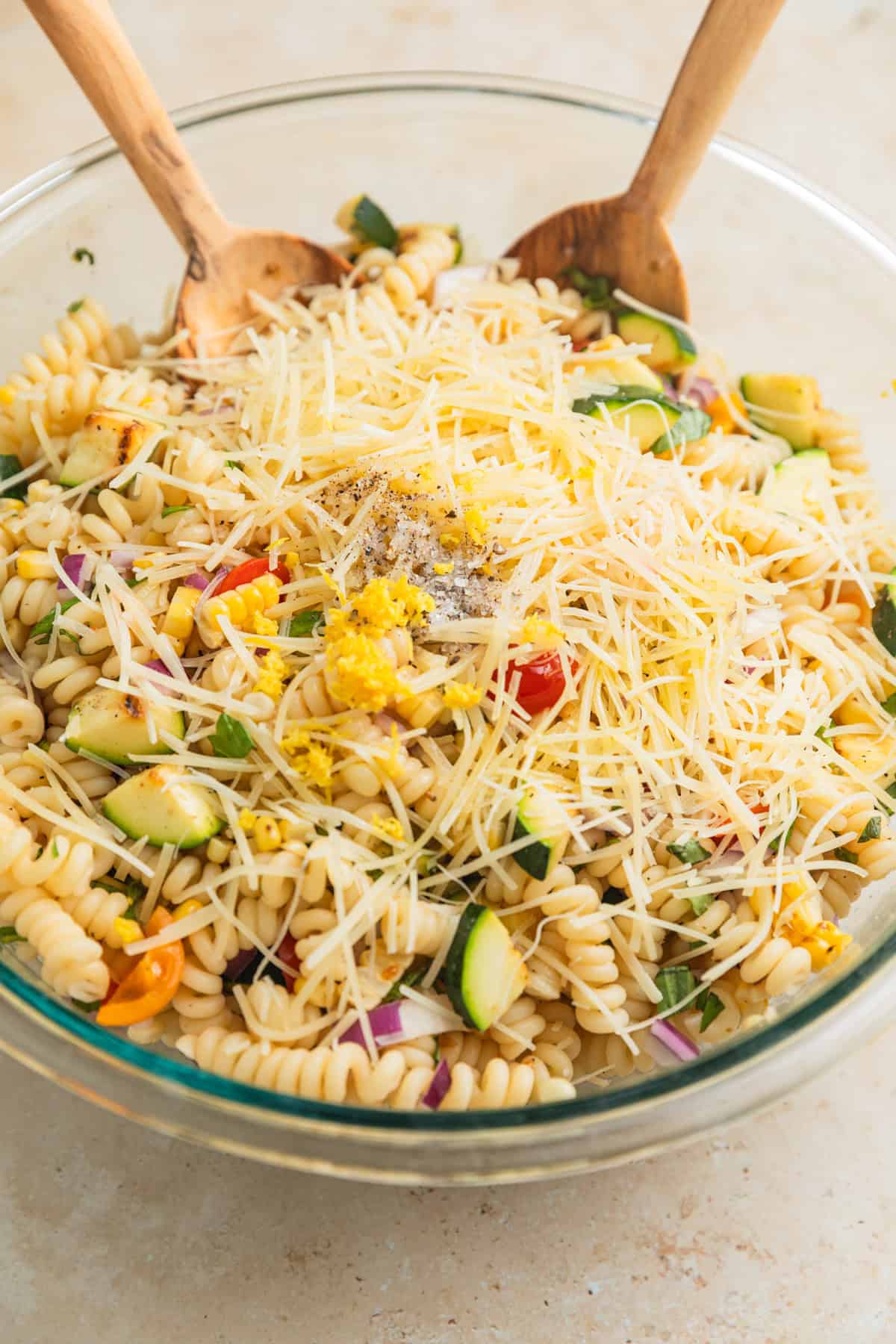 Tossed zucchini pasta salad topped with shredded parmesan cheese, olive oil, lemon zest and more.
