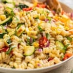 Zucchini pasta salad in serving bowl with wood spoon.