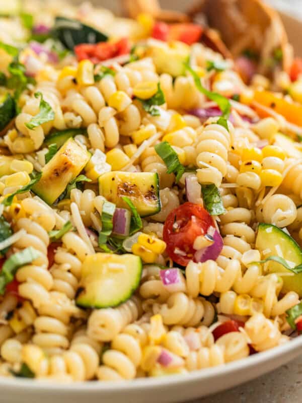 Zucchini pasta salad in serving bowl with wood spoon.