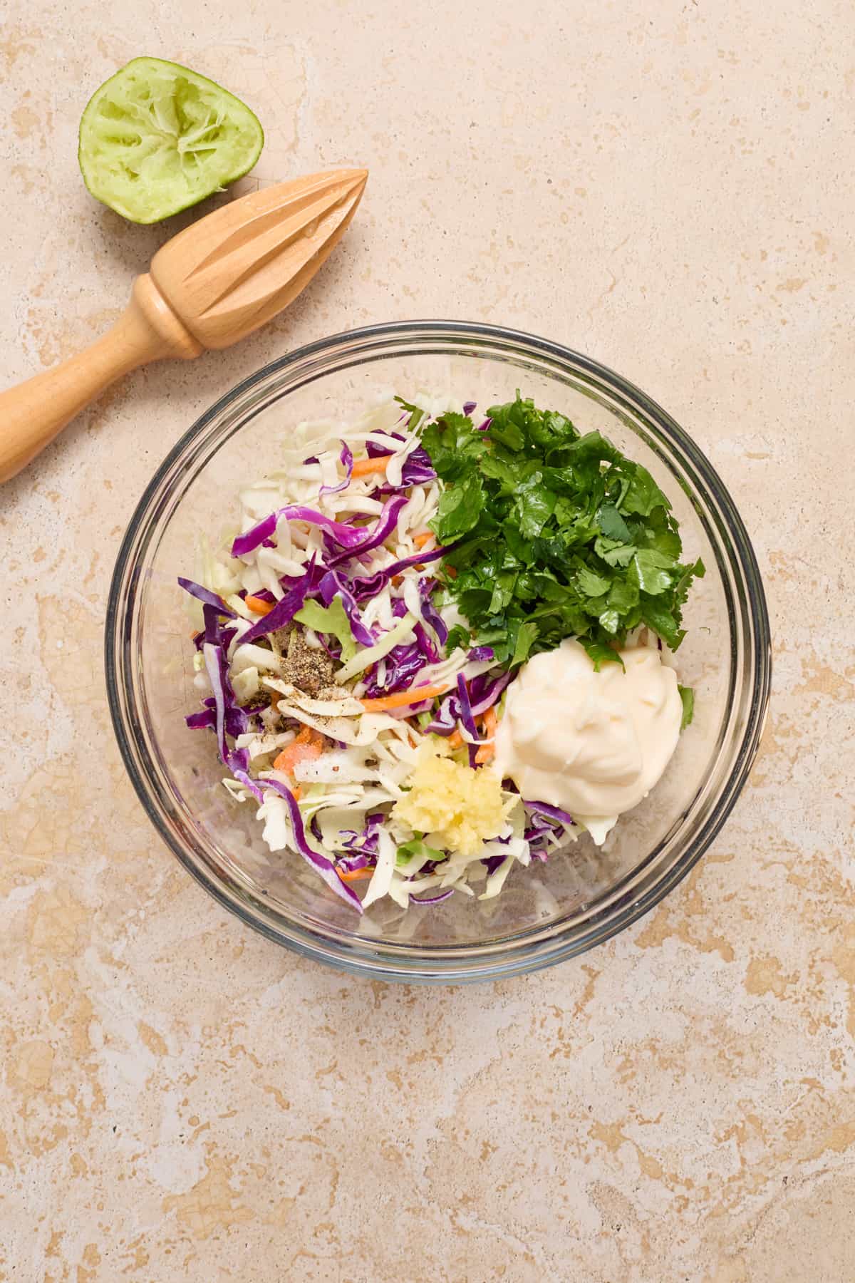 Cilantro lime slaw ingredients in glass mixing bowl.