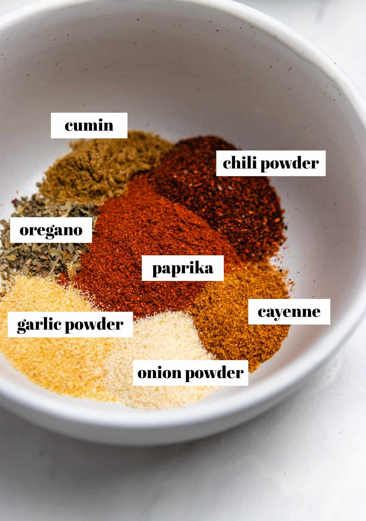 Cayenne, chili powder, oregano, and other spices in bowl.