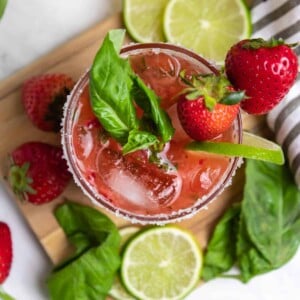 Overhead view of strawberry basil margarita with fresh lime and berries.