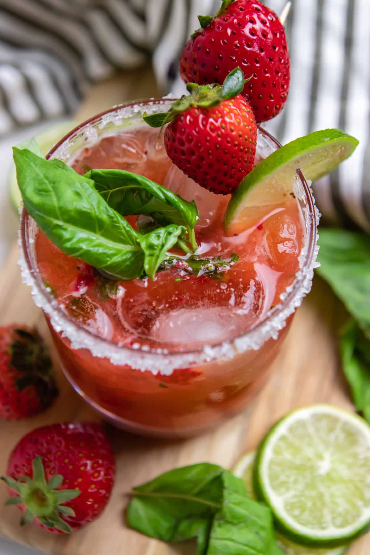 Strawberry basil margarita cocktail with lime and berry garnish.
