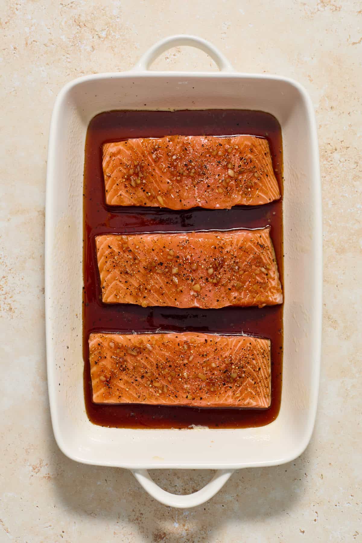 Salmon topped with maple glaze in baking pan.