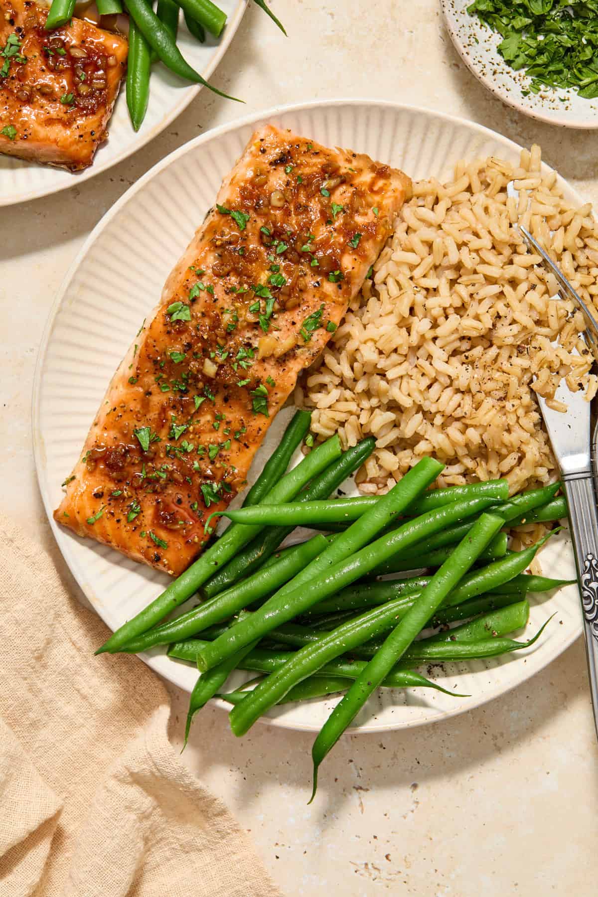 Citrus glazed salmon filet on plate with green beans and brown rice.