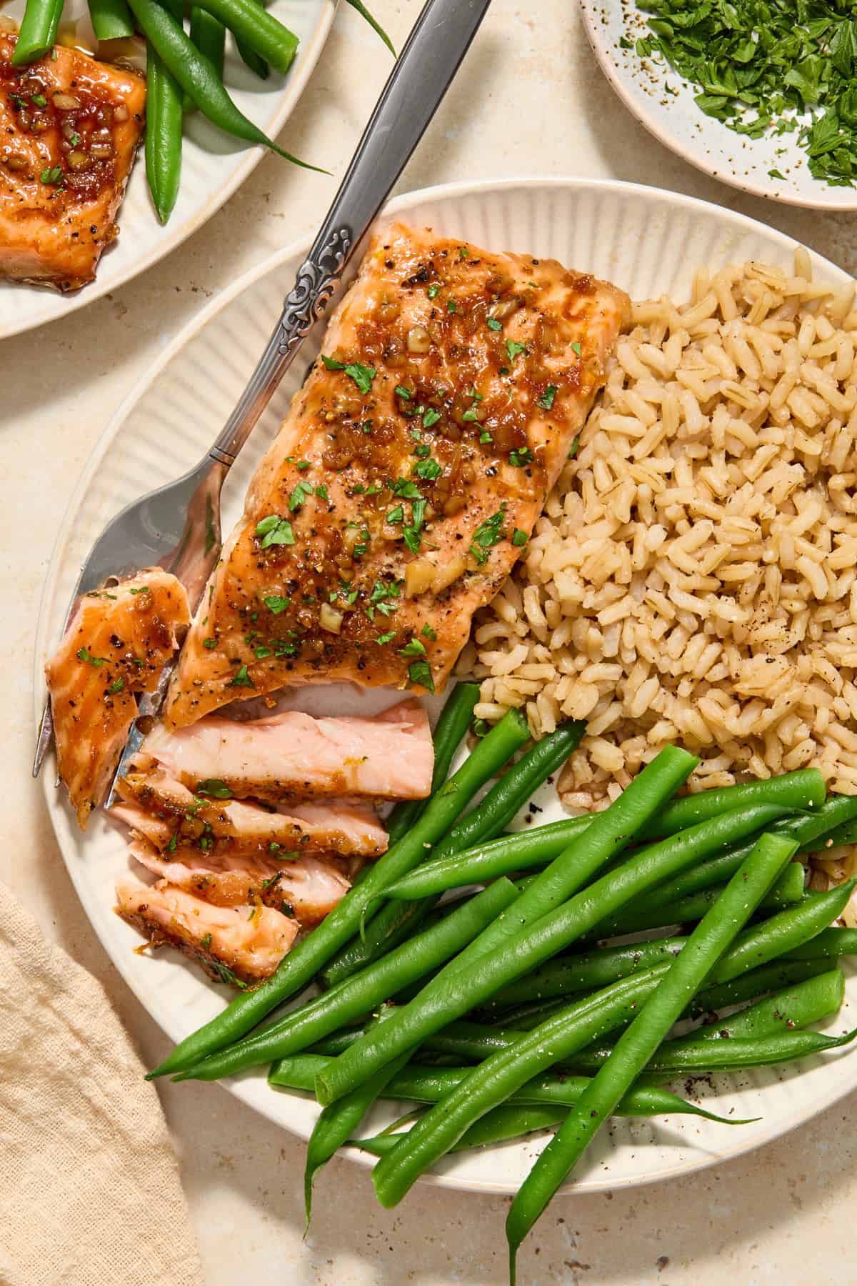 Overhead view of plate with salmon flaked with fork and green beans and rice on plate along with it.