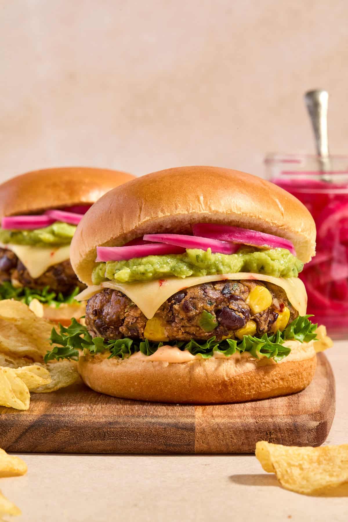 Spicy cilantro lime black bean burgers with chips and jar of pickles onions.