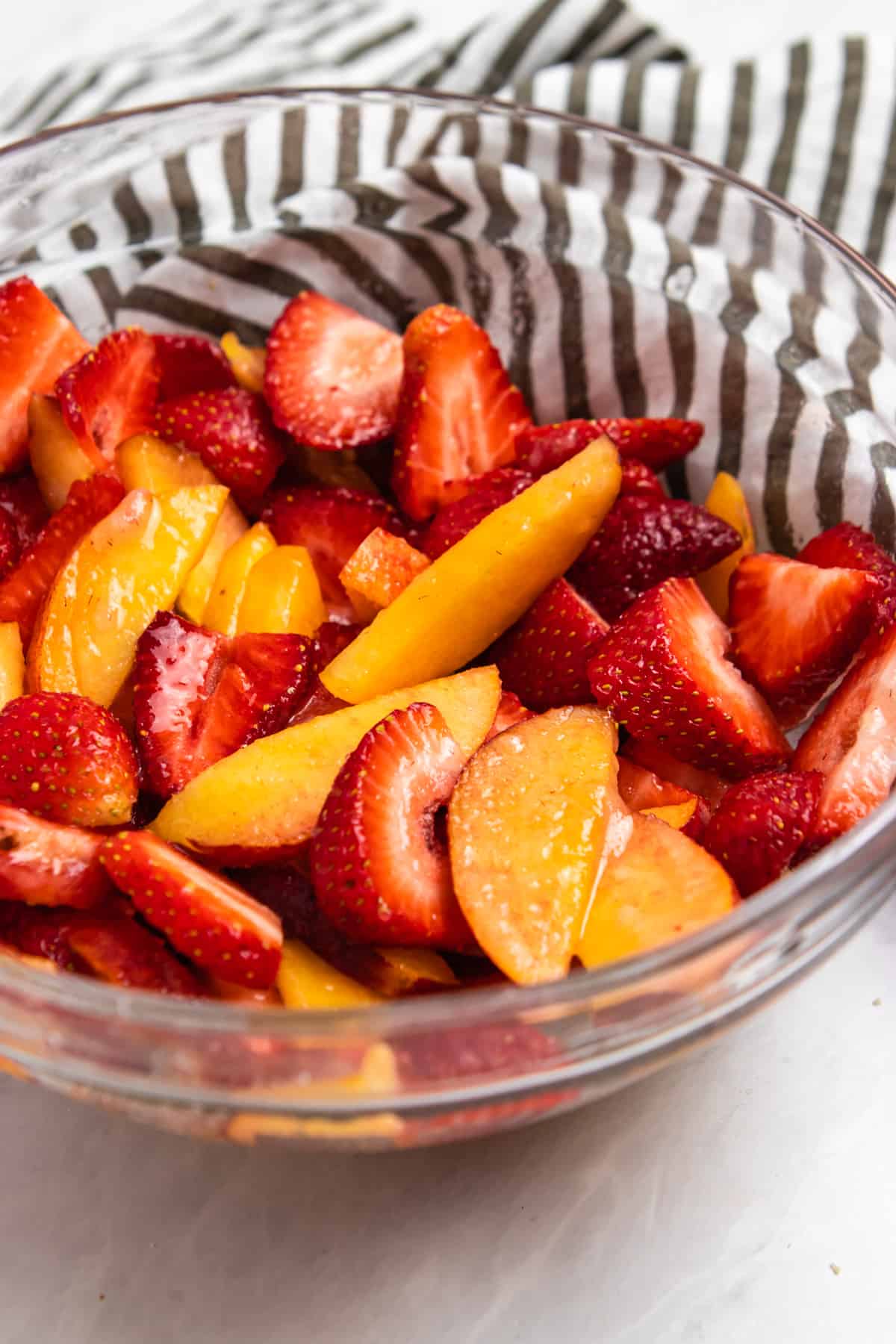 Peaches and strawberries with sugar in bowl.