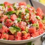 Bowl with watermelon salad with feta and avocado and spoon scooping into it.