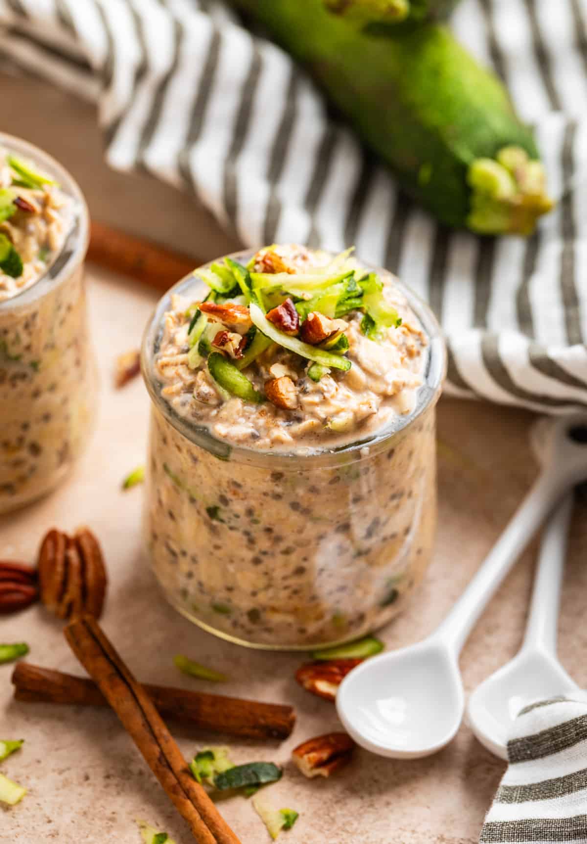 Zucchini overnight oats in jar with shredded zucchini and chopped pecans on top.