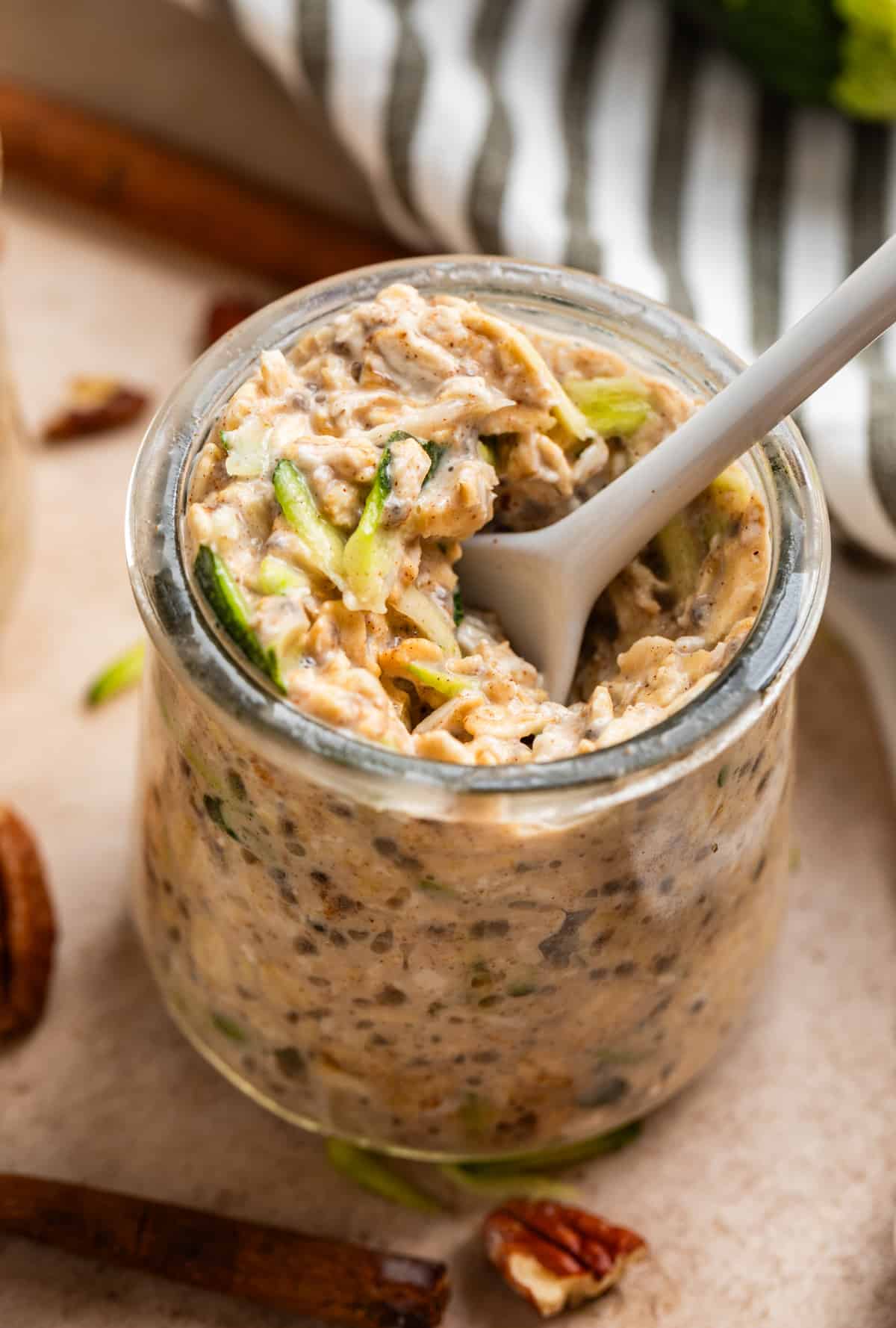 White spoon scooping into a jar of zucchini bread overnight oats.
