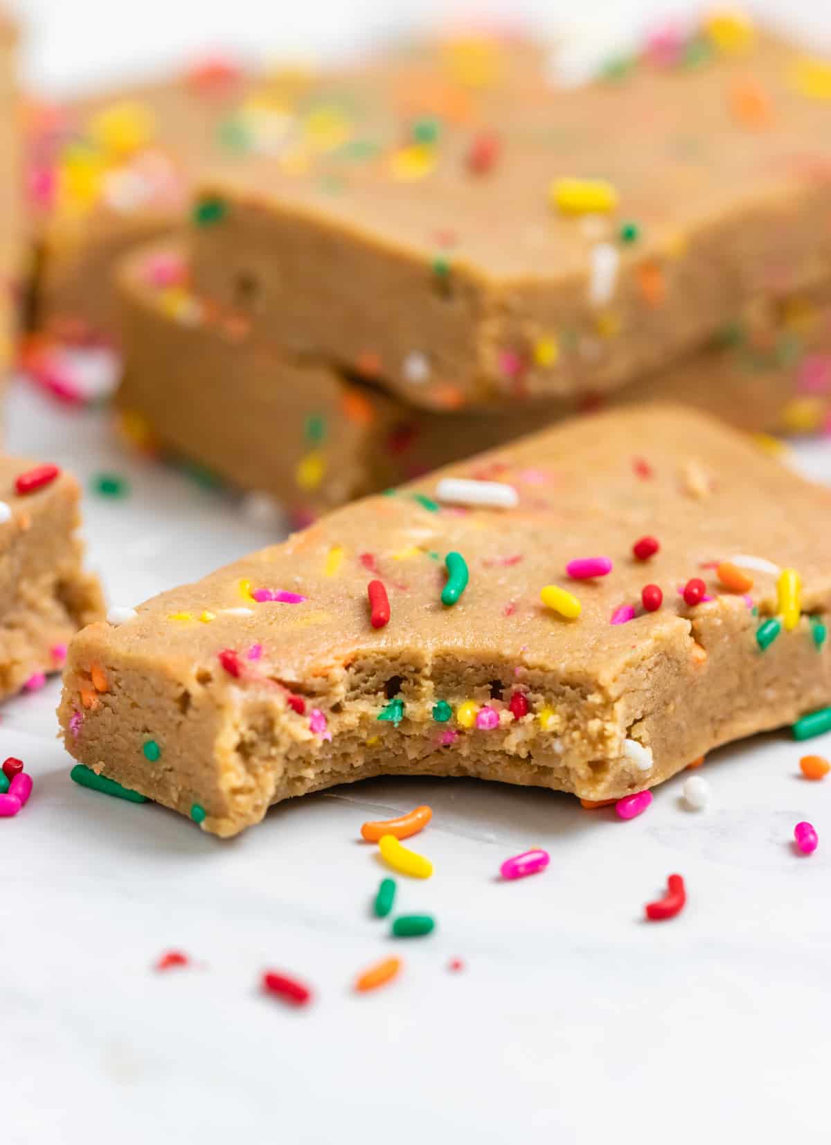 Bite shot of protein bar on counter with rainbow sprinkles.