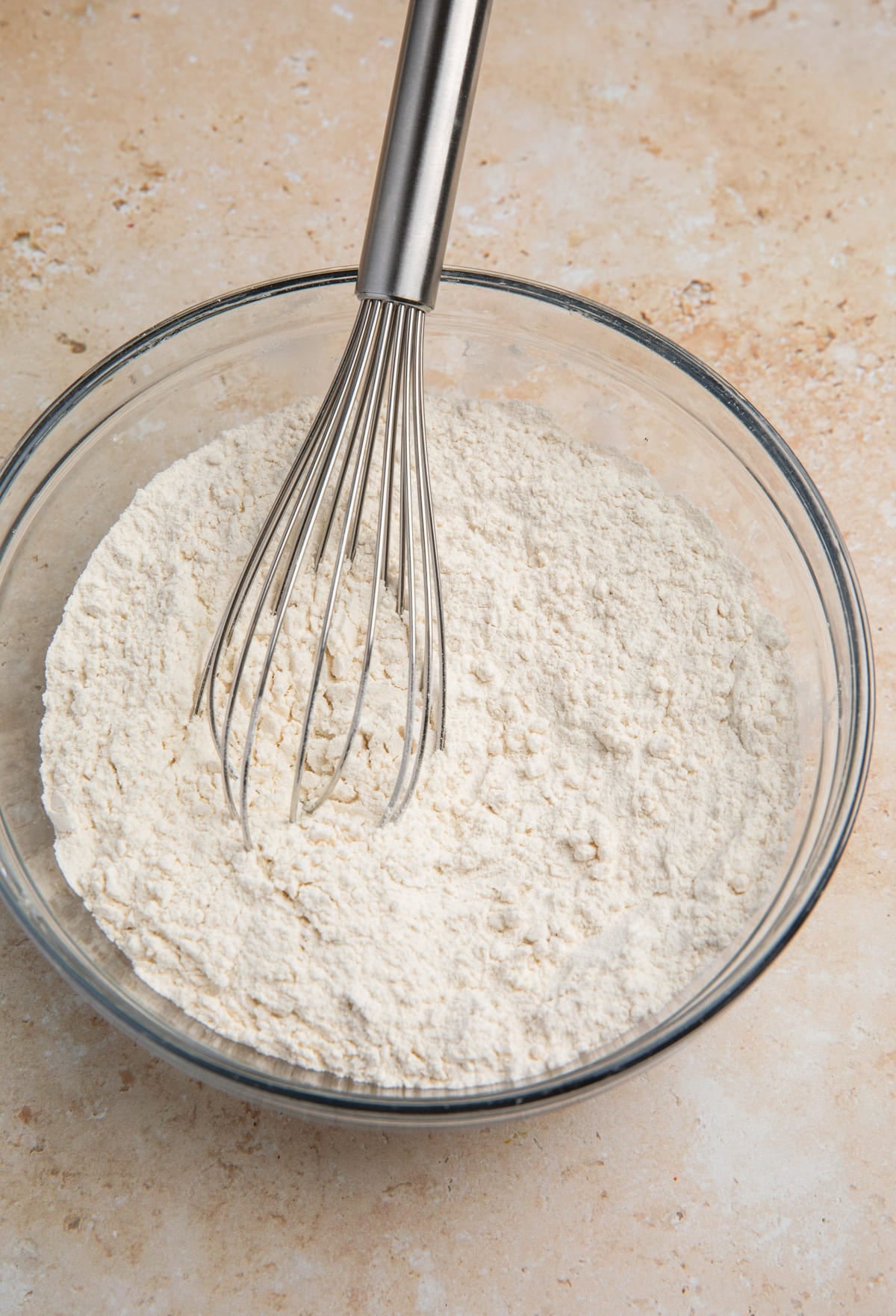 Dry ingredients mixed in glass bowl with whisk.