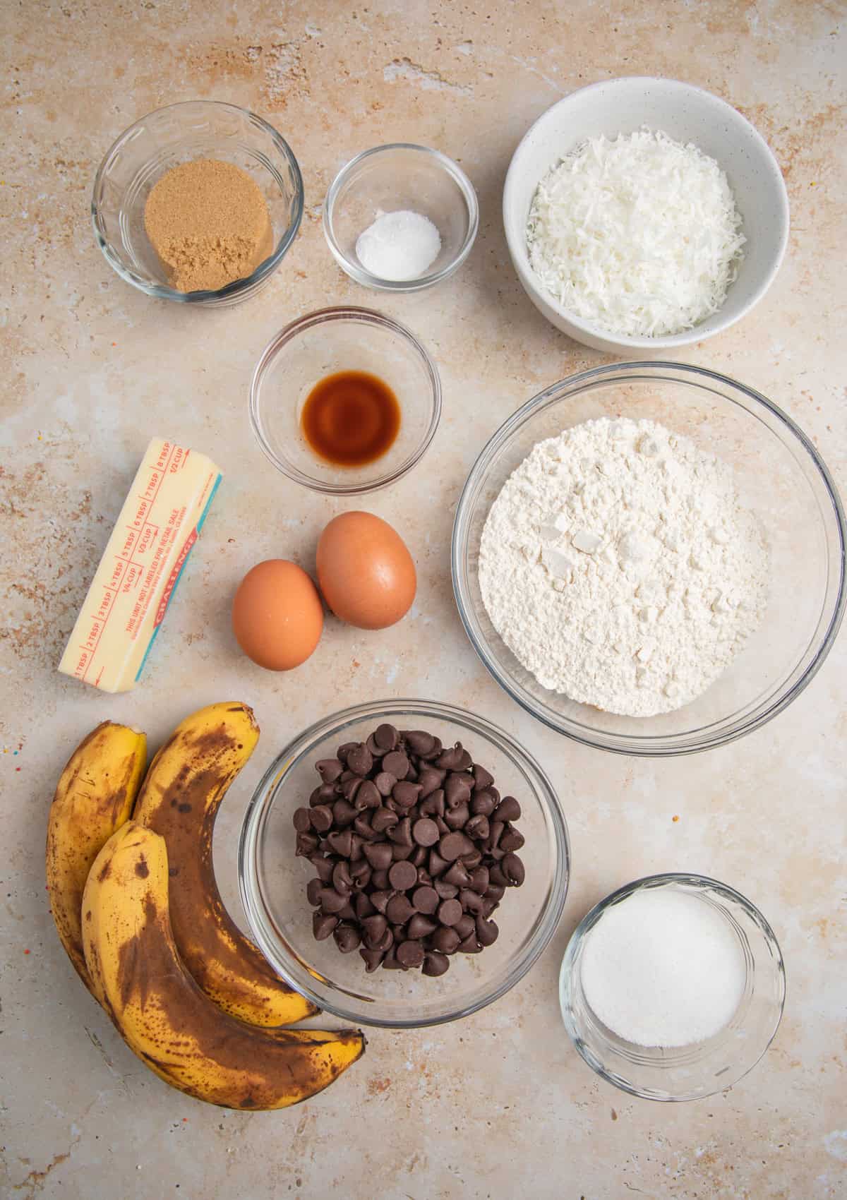 Brown bananas, flour, sugar and other ingredients arranged on surface.
