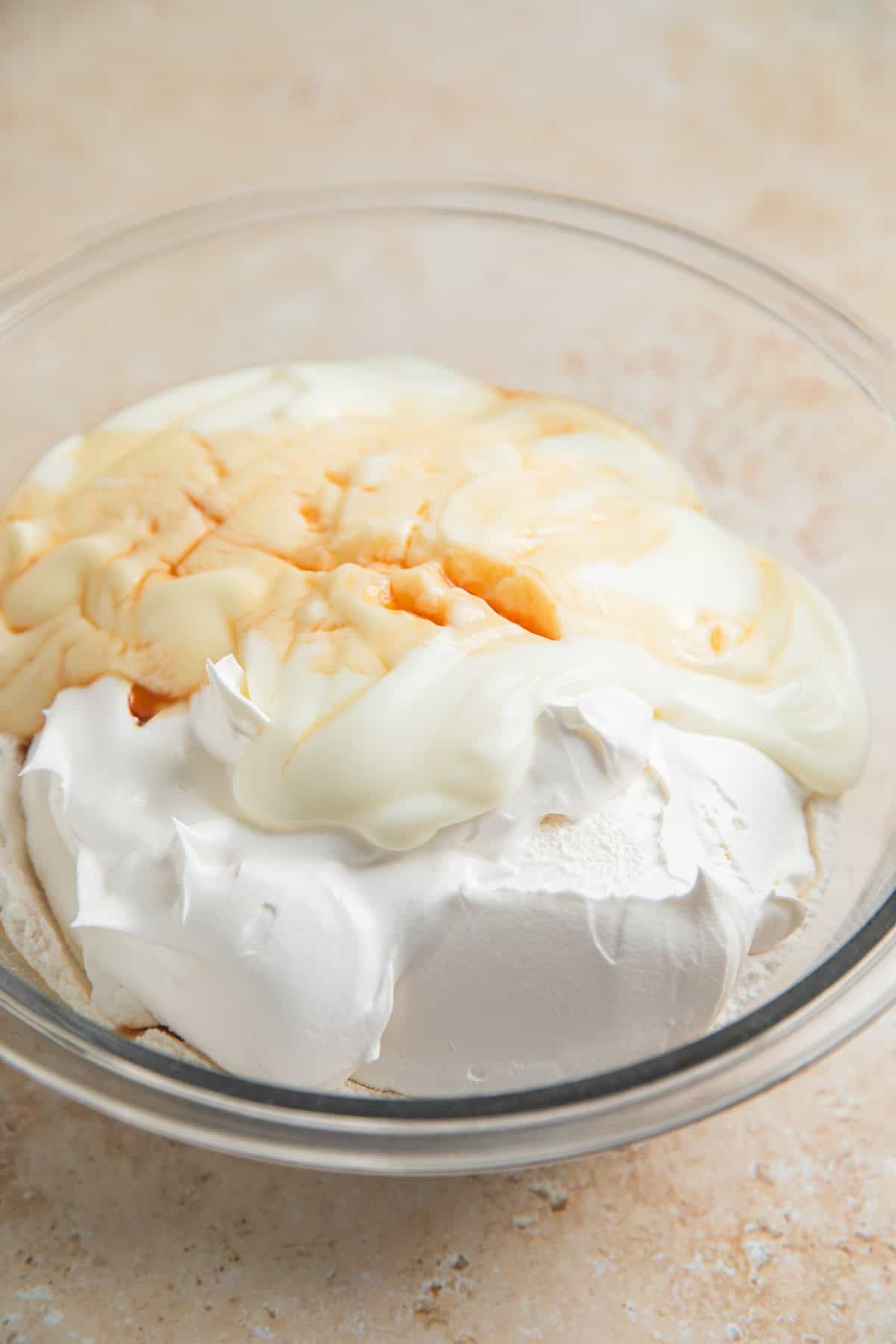 Yogurt, cake mix, cool whip and vanilla in glass bowl.