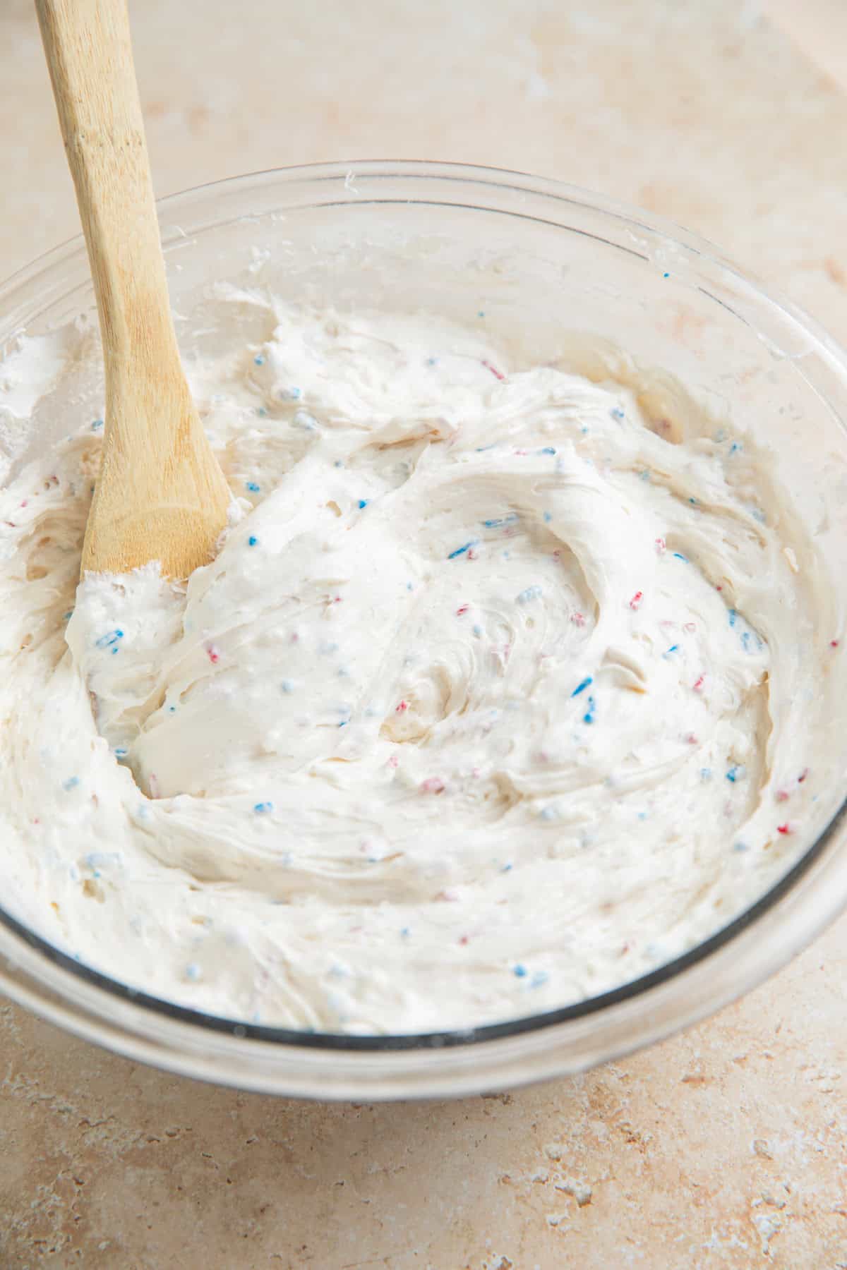 Funfetti dip with sprinkles in glass mixing bowl.
