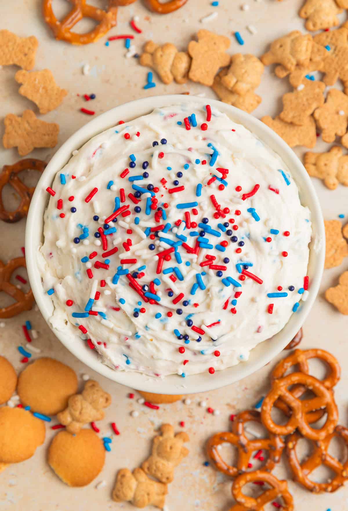 White bowl with patriotic funfetti dip and dippers surrounding.
