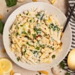 Plate with creamy pasta topped with chopped parsley and lemon zest.